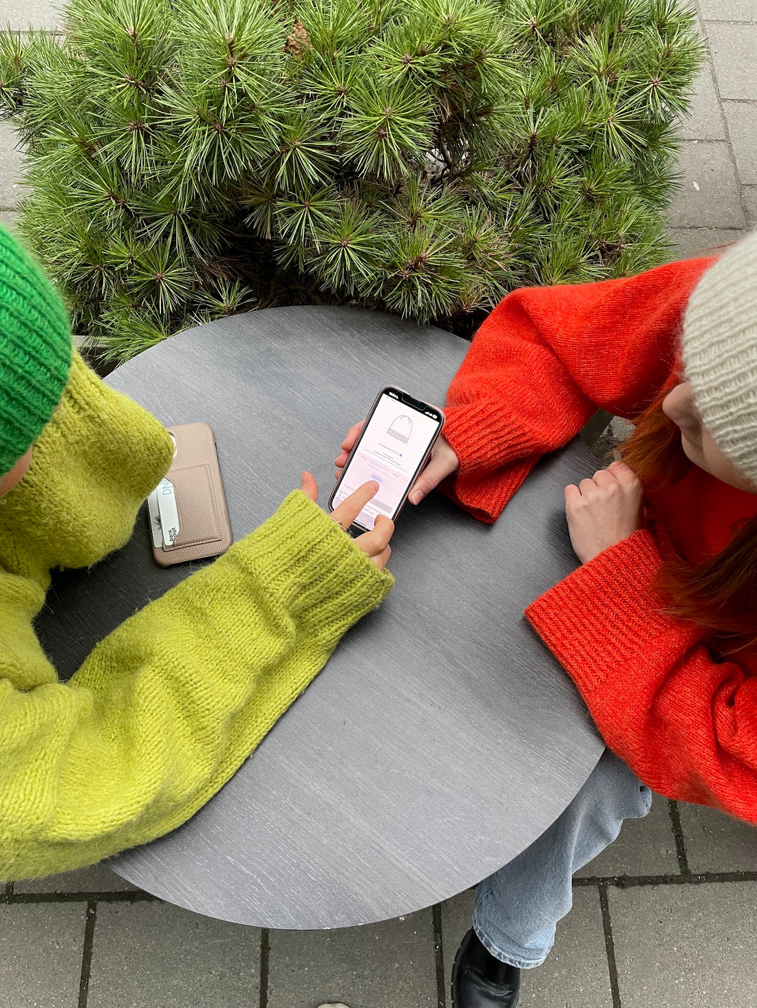 Two girls using Dreamknit's design tool to design their own customized knits. They are wearing knitted sweaters and beanies from Dreamknit 