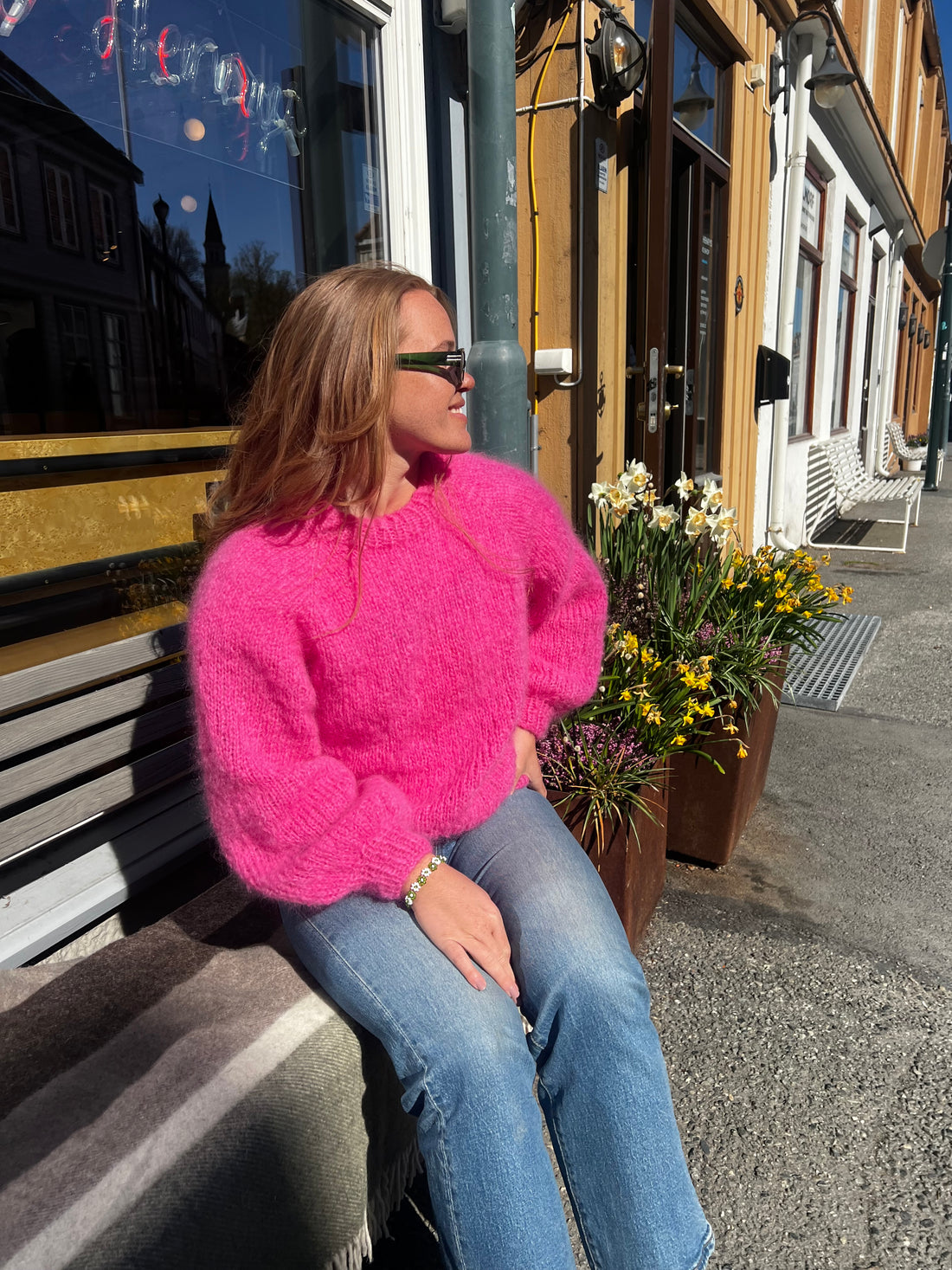 A girl wearing a bright pink knitted sweater outside